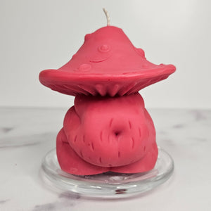 Pink mushroom-shaped body candle on a clear stand with a white background