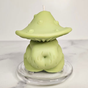 Green mushroom-shaped body candle on a clear stand with a white background