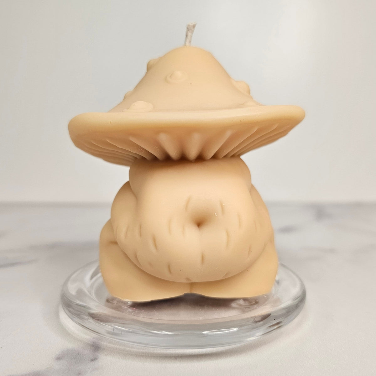 Mushroom-shaped candle on a clear stand with a white background
